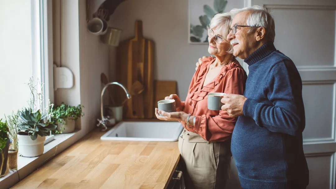 man and woman in kitchen looking out window