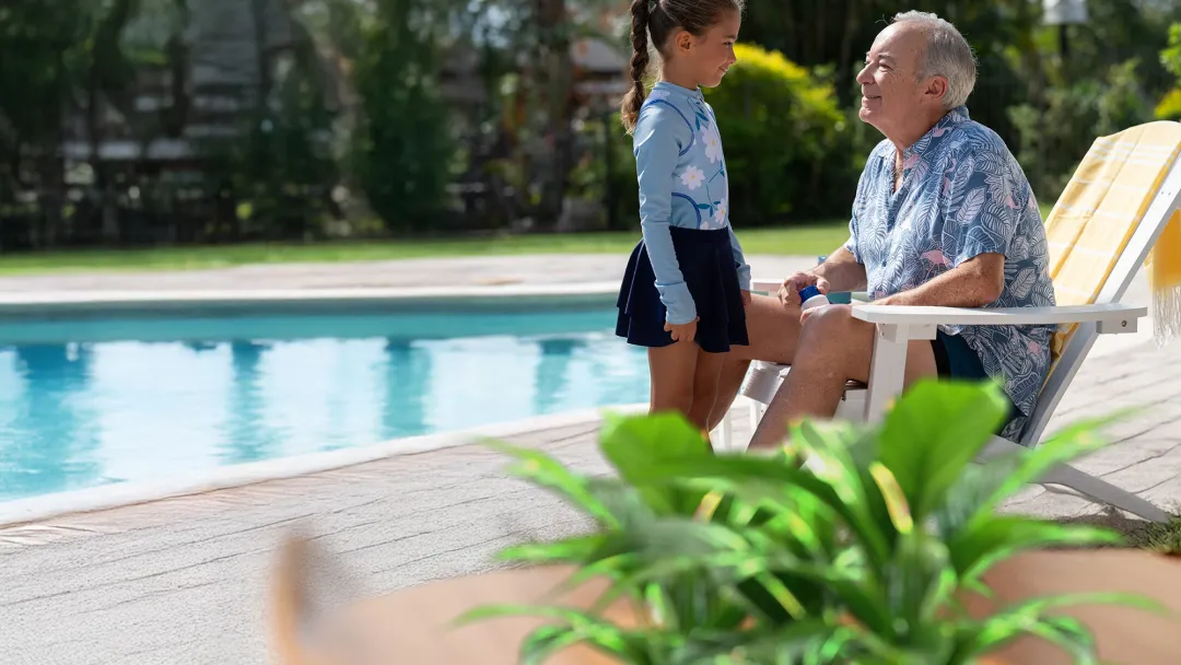 grandpa and granddaughter smiling near pool