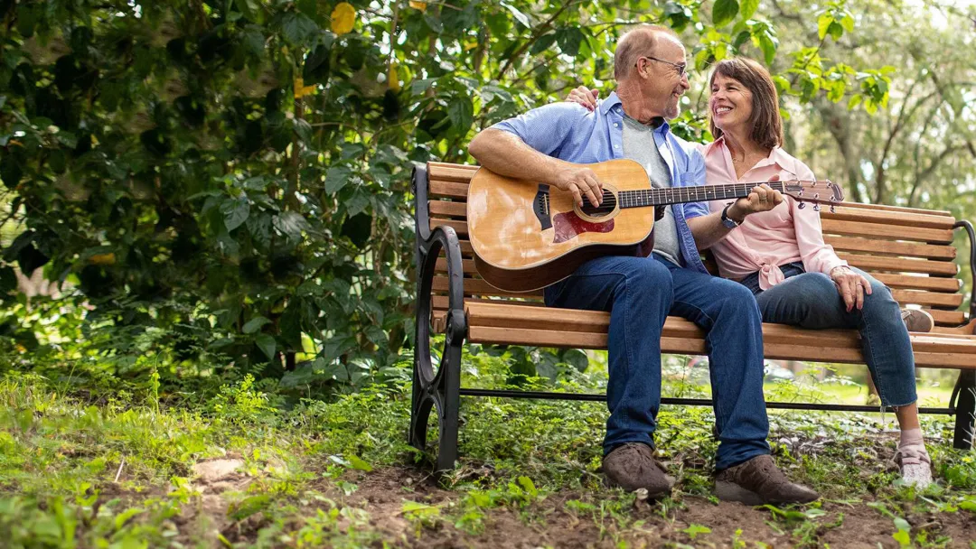 couple seating on a bench with guitar