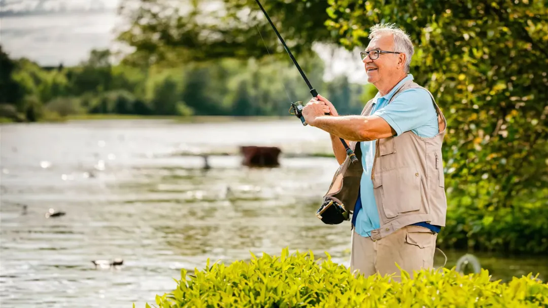 older man fishing by a river