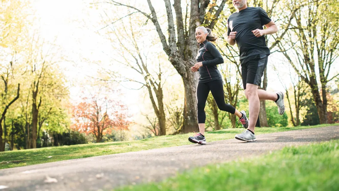Gray-haired couple running in park