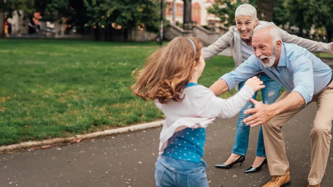 Grandparents greeting granddaughter in park
