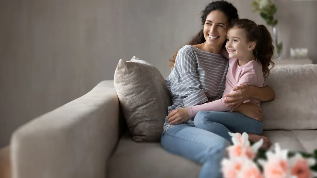 mother and daughter in a livingroom smiling and hugging