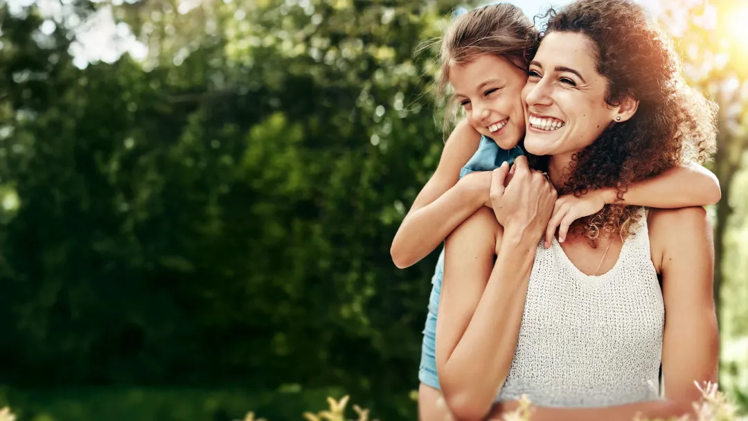 mother and young daughter hugging outside