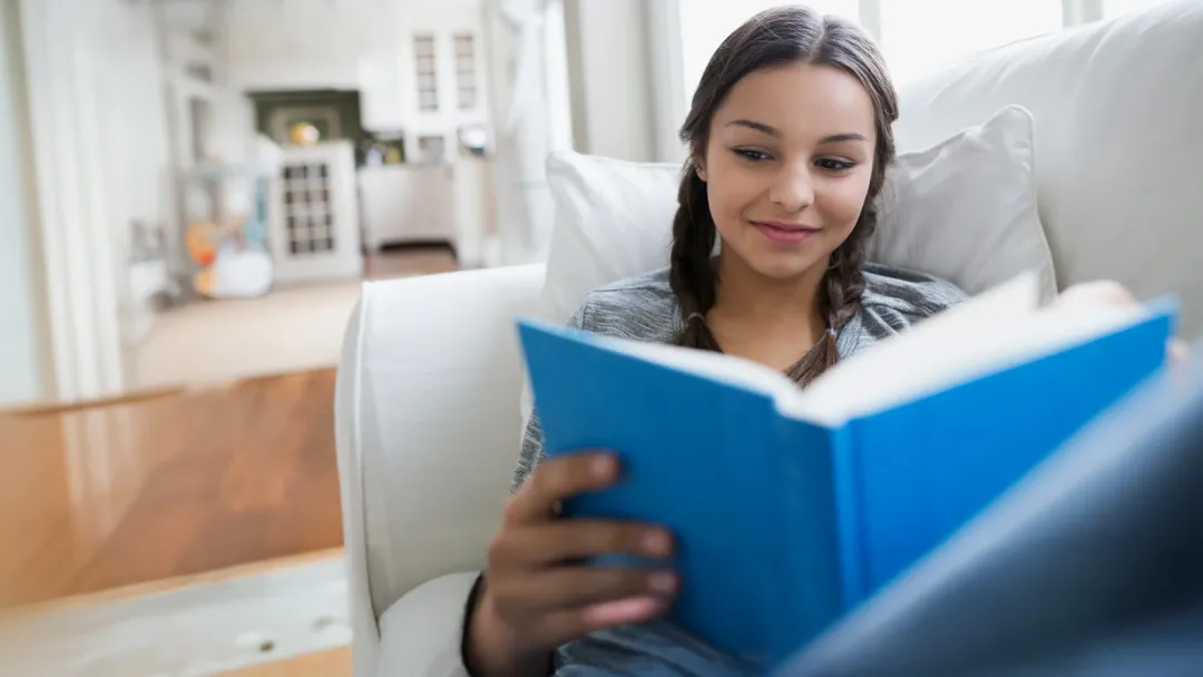girl reading a book on a couch