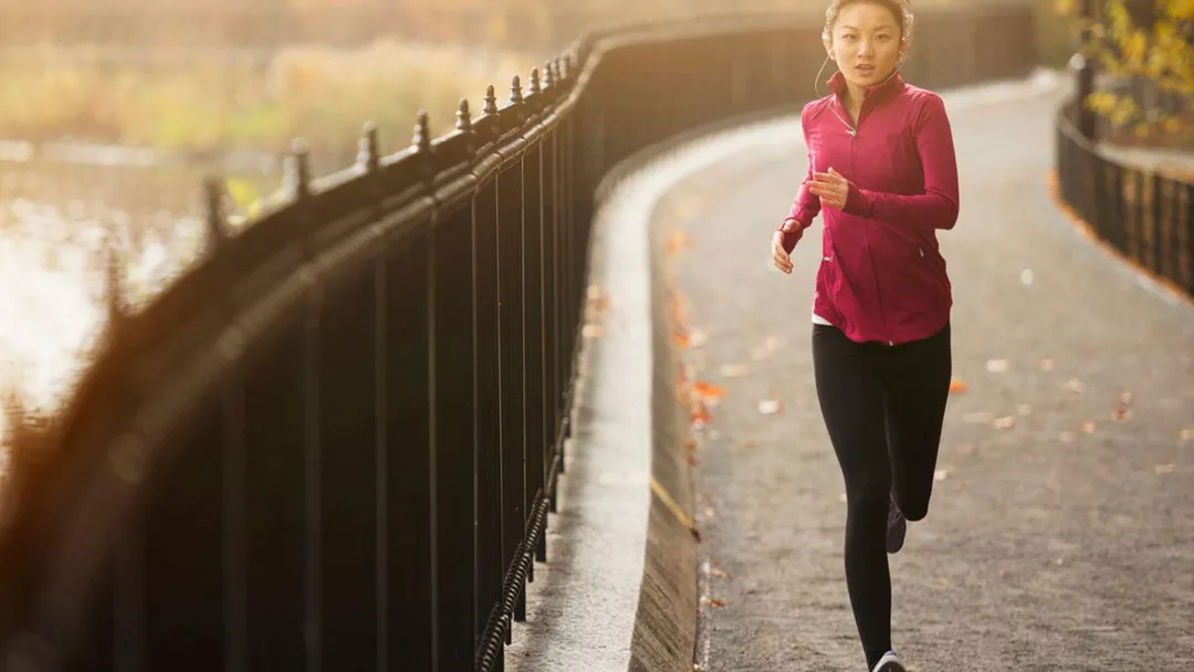 woman running outside on path next to a lake
