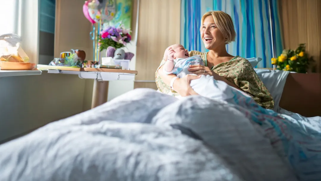 a woman happy to gold her new born baby