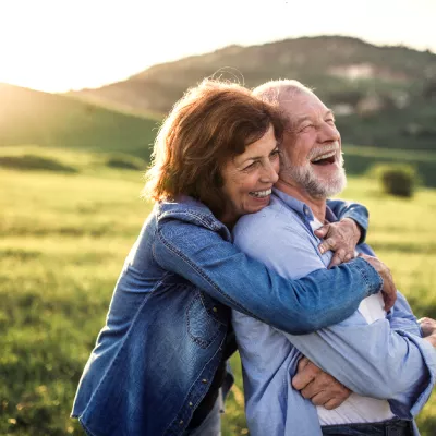 Older couple embracing next to hill at sunset