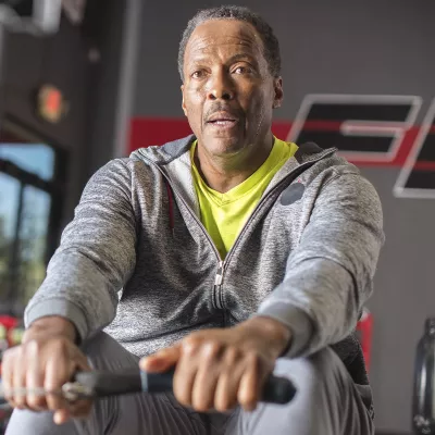 An African American man exercises on a rowing machine at the gym.