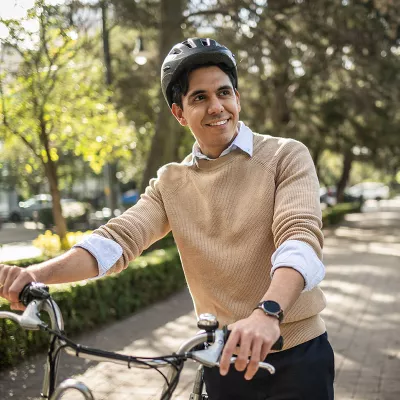 A Hispanic man riding bike in city wearing a helmet