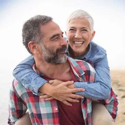 Man giving woman piggy back ride on beach