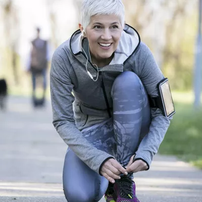 woman tying her shoes and smiling outdoors