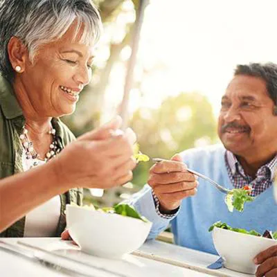 Senior couple eating salad outdoors