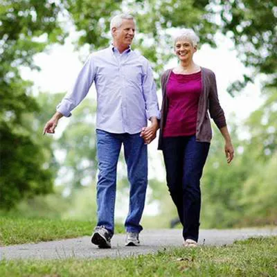 Senior couple walking through park holding hands