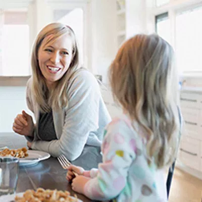 Mother talking to young daughter at table