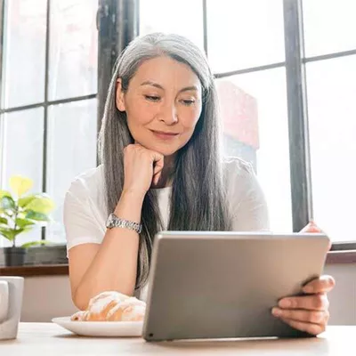 Woman smiling next to window with tablet