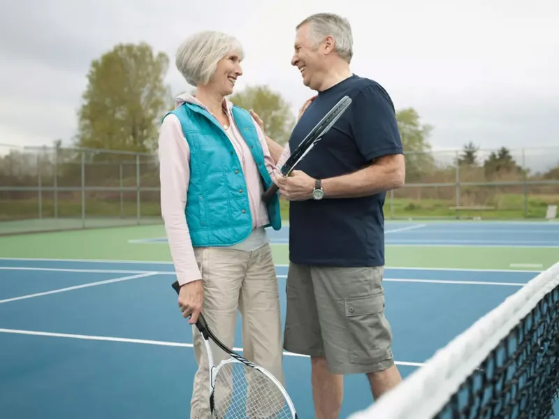 couple playing tennis and laughing