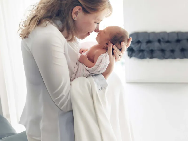 Woman holding newborn and touching noses