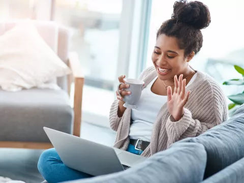 A woman waving to a friend on a video call.