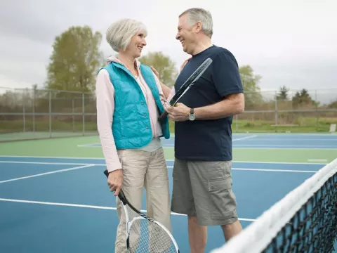 couple playing tennis and laughing