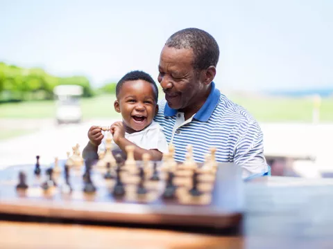 Grandfather and grandson playing chess outdoors