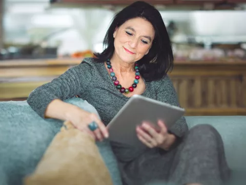 woman seating reading her tablet and smiling