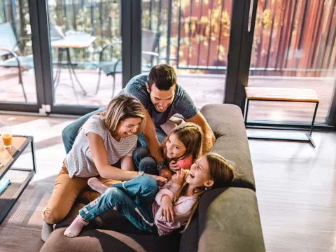 Parents tickling kids on couch at home