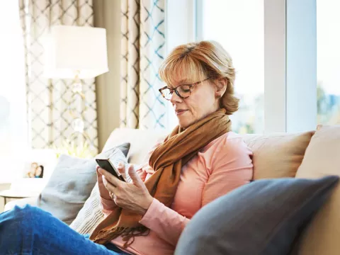 Senior woman using phone on couch at home