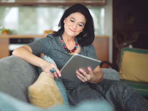 Dark-haired woman relaxing on couch with tablet