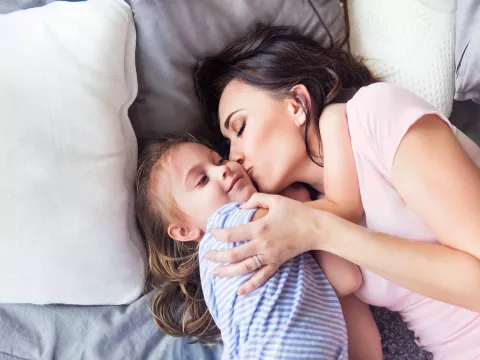 Mother embracing daughter on bed