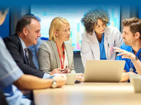 Executives and doctors in a conference room with a laptop and projected chart