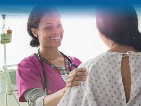 Nurse smiling at female patient in gown