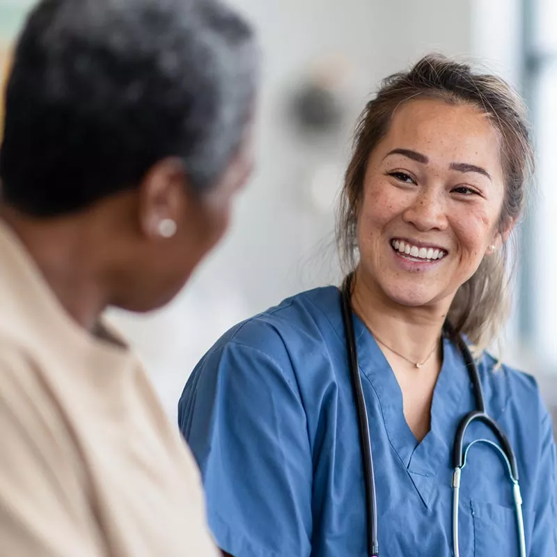 Female nurse in blue smiling at woman