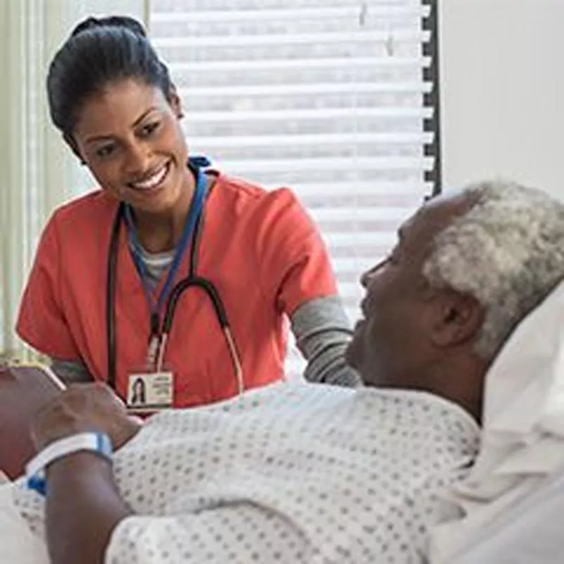 Female nurse smiling at old man in bed