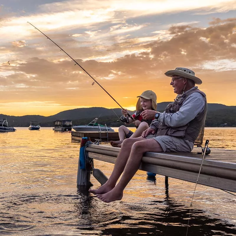 Grandfather and grandchild fishing at sunset