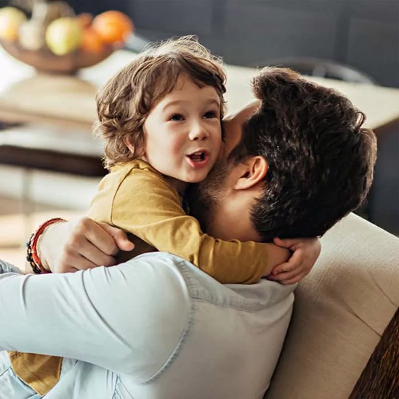 Father hugging his son on couch