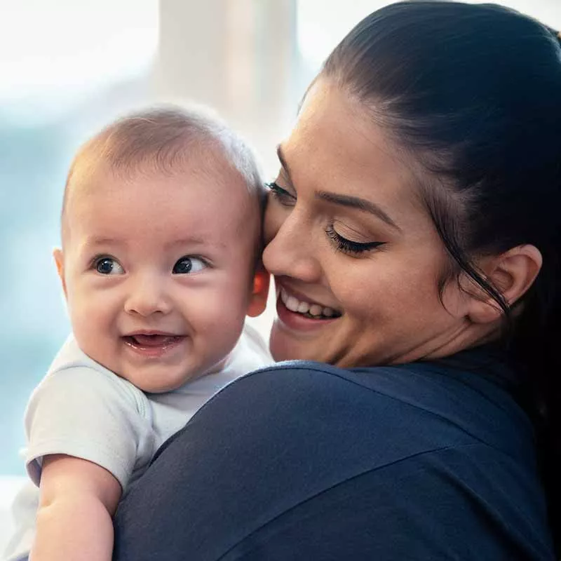 Close-up of a woman holding a baby, both smiling