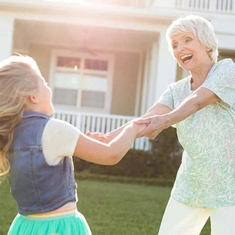 Grandmother and girl dancing in yard