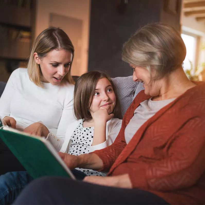 Grandmother mother and girl reading on couch