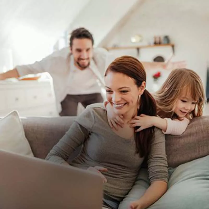 Mother on computer with daughter and husband behind