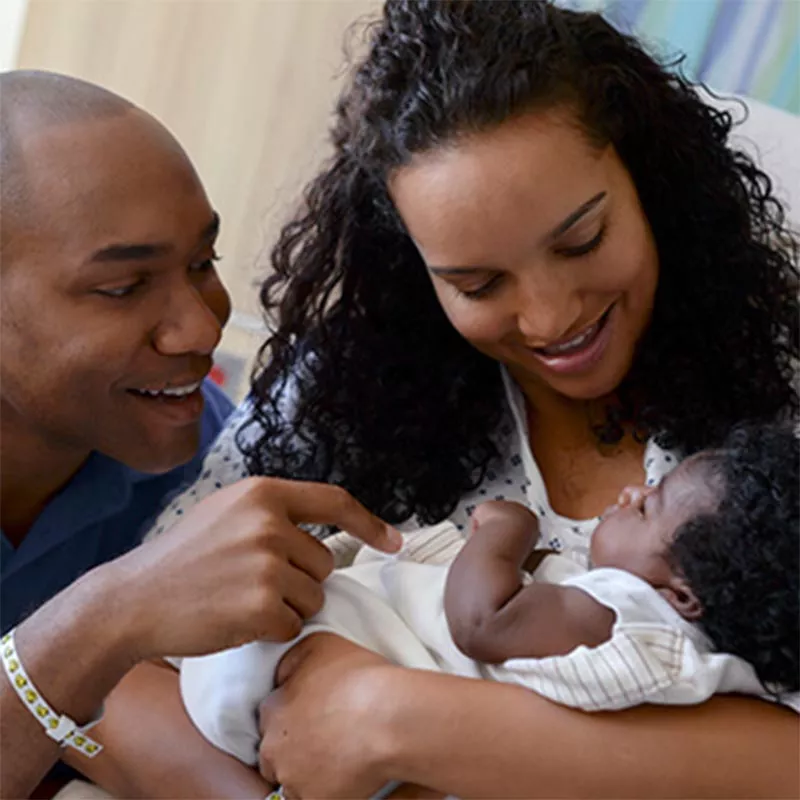 Black mother and father smiling at newborn