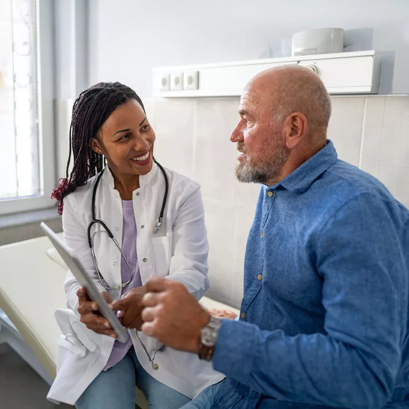 a physician-with-a-tablet-converses-with-patient