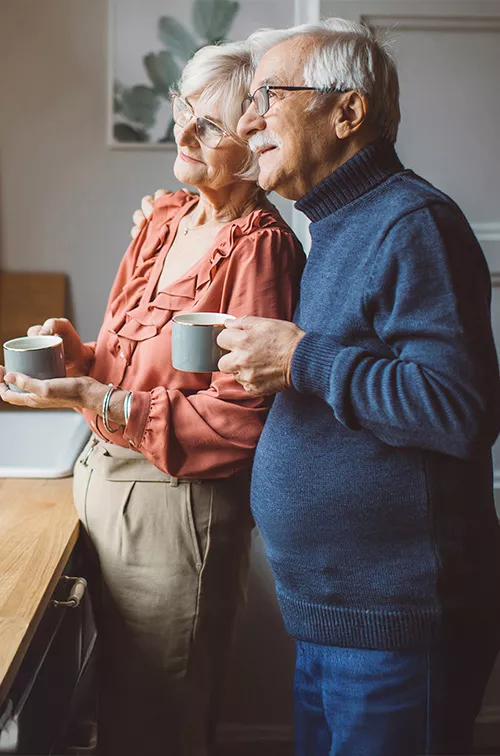 man and woman in kitchen looking out window