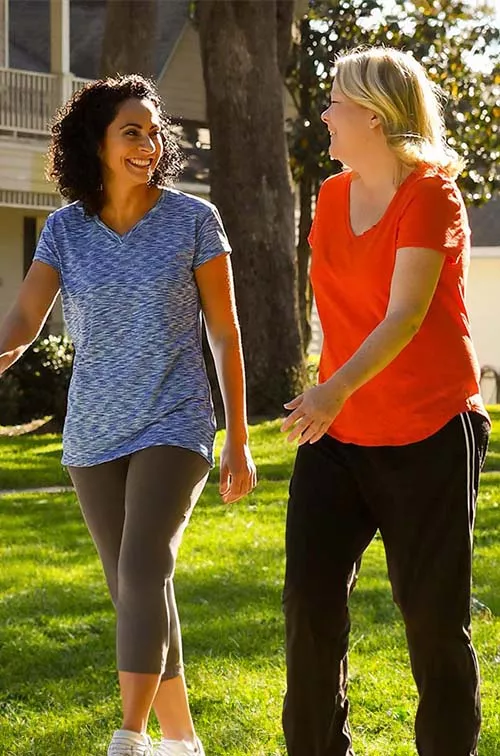 Two women walking and smiling in a neighborhood