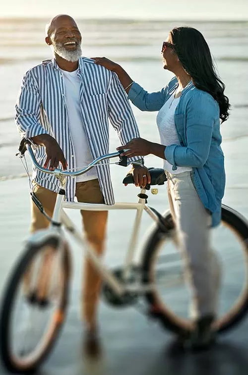 Couple smiling with bicycle on beach