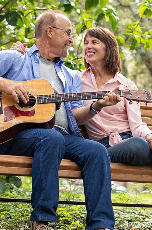 couple seating on a bench with guitar