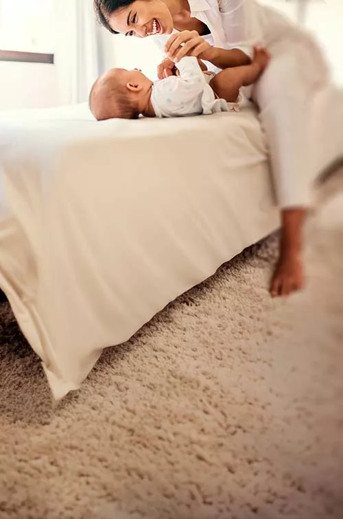 Woman playing with baby on bed