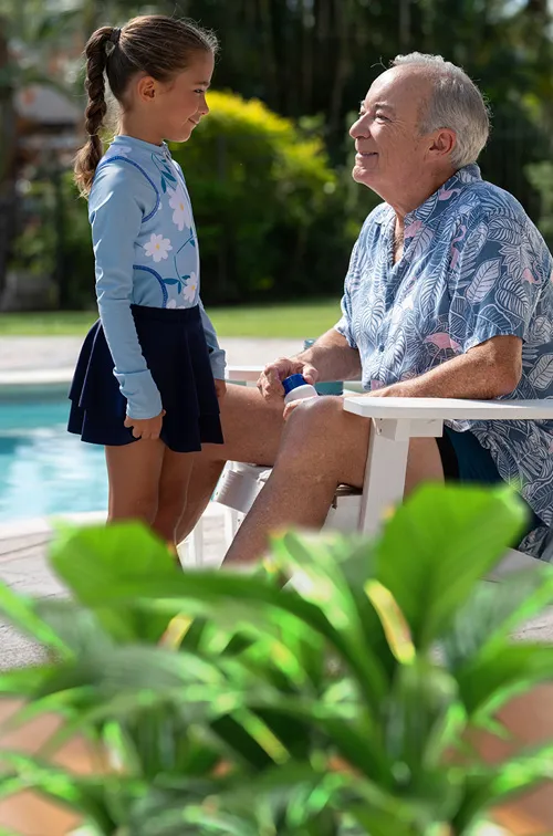 grandpa and granddaughter smiling near pool