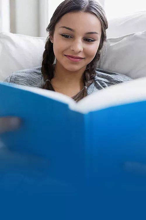 girl reading a book on a couch