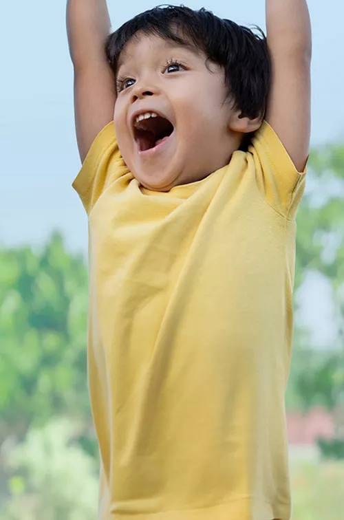 a boy raises his arms and laughs outdoor